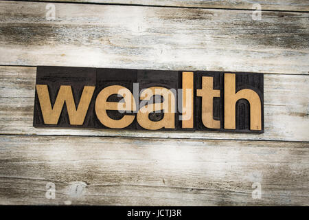 The word "wealth" written in wooden letterpress type on a white washed old wooden boards background. Stock Photo