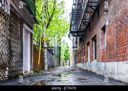Montreal, Canada - May 26, 2017: Empty street alley in Plateau area of city in Quebec region during wet rain on cloudy day with puddles Stock Photo