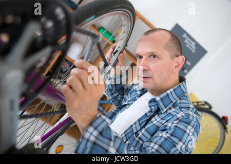 middle-age man repairing bike gear in his workshop Stock Photo