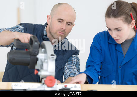 female apprentice using circular saw in carpentry workshop Stock Photo