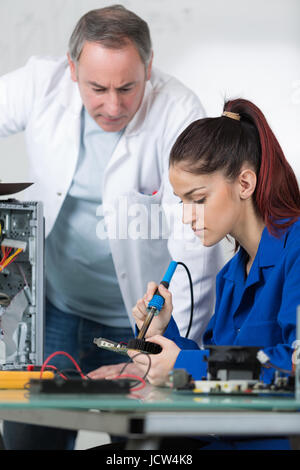teacher supervising student soldering mother board of computer Stock Photo