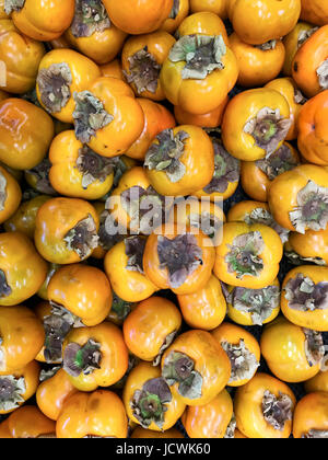 Organic persimmon fruits in pile at local farmers market. persimmon background. Stock Photo