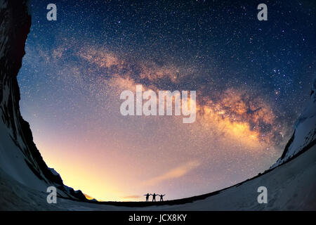 Silhouettes of the people standing together holding hands with the Milky Way above them. Captured in Nepal, Annapurna Conservation Area, Thorung Pass. Stock Photo