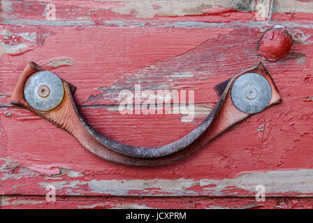 Worn leather handle on old red wooden door Stock Photo