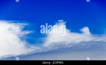 Puffy white clouds on a clear blue sky background Stock Photo