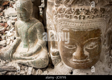 Stone carved Buddha and Khmer head as seen at the Bayon Temple within the Angkor Wat complex of Temples in Siem Reap, Cambodia Stock Photo
