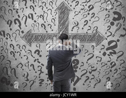 Confused businessman looking at arrow directional signs and question marks Stock Photo