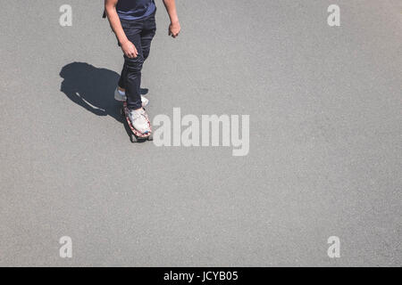 young man on skateboard on asphalt road with copy space from above - Stock Photo