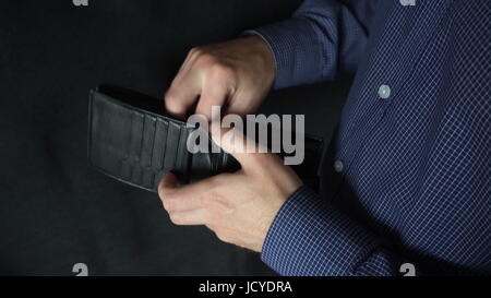 the man rummages in the purse,and then pulls out his hundred dollar bill. Stock Photo