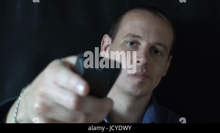 young man sitting in front of the camera and switches the channels,watching TV. Stock Photo