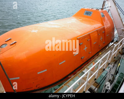 A lifeboat in case of an accident in the port or on a ship. The orange boat. Stock Photo