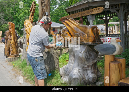 Wood carving artist Fred Steffen varnishing a piece for sale at his roadside stand near the LIE in Manorville, New York. Stock Photo