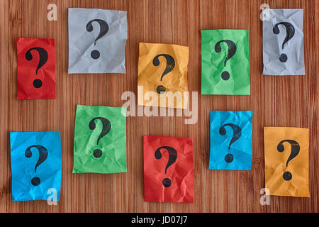 Colorful paper notes with question marks on a wooden background. Concept image. Stock Photo