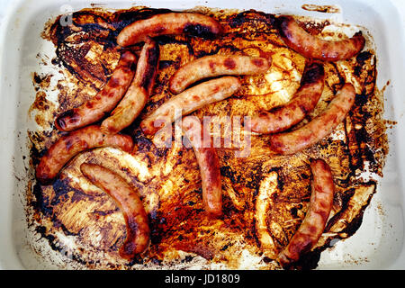 12 sausages cooking in a white dish Stock Photo