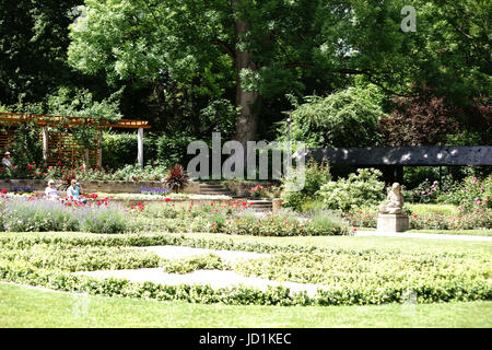 Mainz, Germany - June 10, 2017: Visitors of the Volksspark Mainz sit on park benches in the semi-shade of a garden area on June 10, 2017 in Mainz. Stock Photo