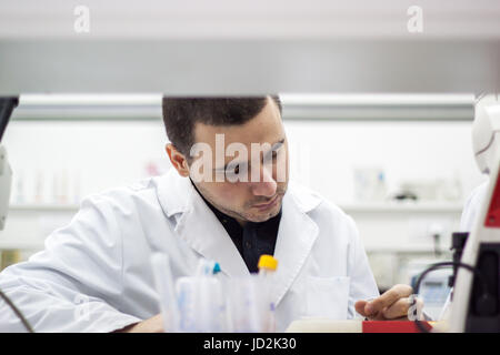 Young doctor conducts research, and it is very concentrated and focused on what he is doing Stock Photo