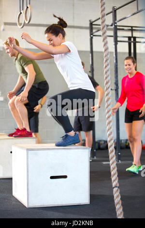 Determined Athletes Doing Box Jumping In Health Club Stock Photo