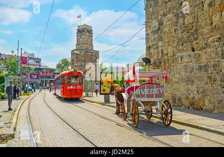 ANTALYA, TURKEY - MAY 6, 2017: The trams and horse carriages in Cumhuriyet avenue next to the Clock Tower (Saat Kulesi) and preserved ramparts, on May Stock Photo