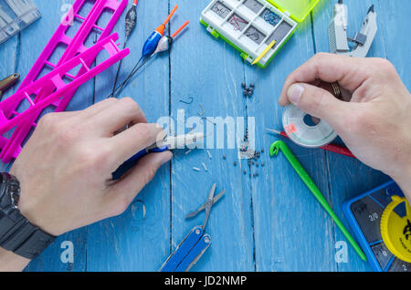 The fisherman is preparing for fishing. The fisherman knits the pile. The fisherman ties the fishing line to the hook. Stock Photo
