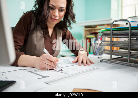 Beautiful architect at her working desk with blueprints in front Stock Photo