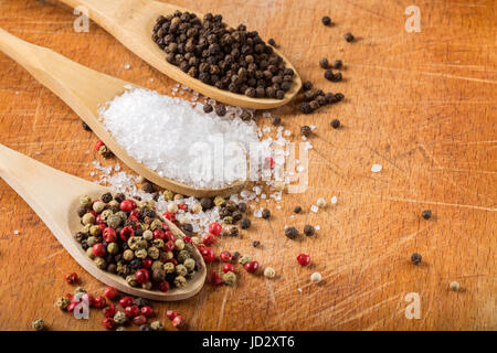 Wooden spoons with sea salt and peppercorns on wooden background with copy space. Macro with shallow dof. Stock Photo