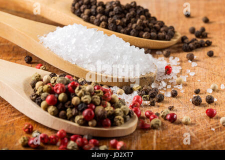 Wooden spoons with sea salt and peppercorns on wooden background. Macro with shallow dof.