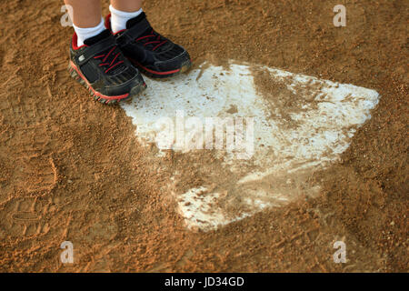 young child makes it to home plate, focused on close up of feet and baseball diamond Stock Photo