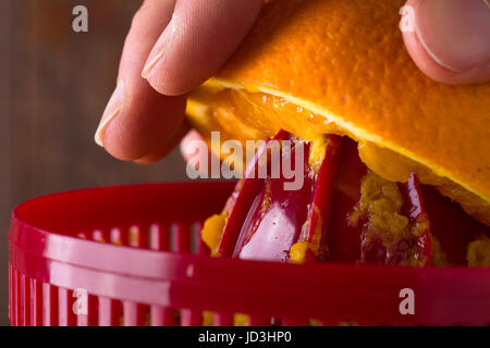 Hand Squeezing an Orange with an Orange Juicer Stock Photo