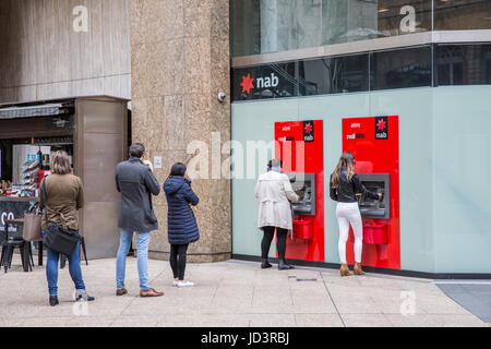 Customers queue to withdraw cash from National Australia Bank NAB cashpoint ATM machines in Sydney,Australia Stock Photo