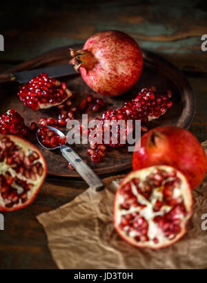 Red juicy pomegranate, whole and broken, on rustic background Stock Photo