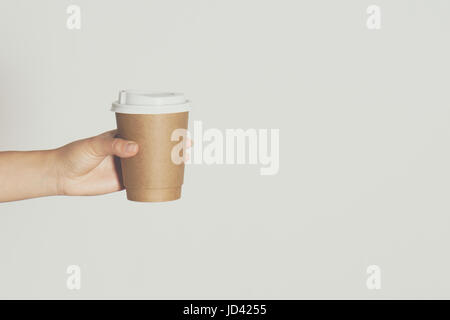 Womans hand holding brown paper cup of hot coffee. Stock Photo
