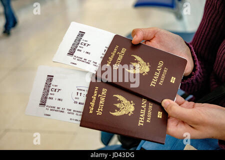 Two of Thailand passports in hands with boarding passes. Stock Photo
