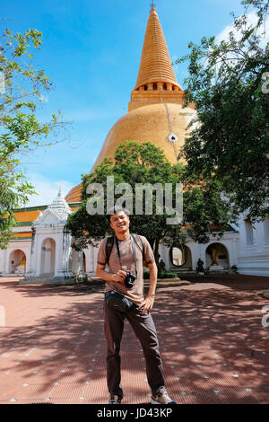 Tourist man with camera standing in front og thai pagoda temple. Stock Photo