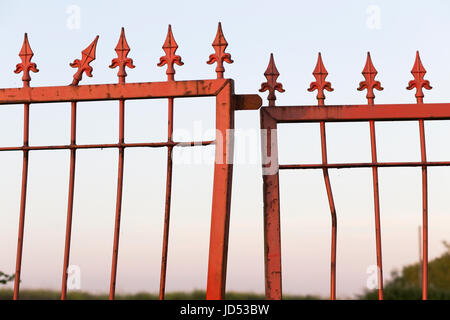 Red-painted rusty and bent steel gate with finials. Stock Photo