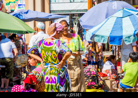 SAMARKAND, UZBEKISTAN - AUGUST 28: Two women dressed in traditional Uzbek clothes talking and counting money at Siab bazaar, local market in Samarkand Stock Photo