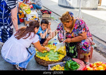 SAMARKAND, UZBEKISTAN - AUGUST 28: Woman picking ripe yellow figs out of the basket at Siab bazaar, local market in Samarkand. August 2016 Stock Photo