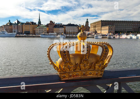 Golden crown on Skeppsholm bridge with Stockholms slot (royal palace) in the background. Stockholm, Sweden Stock Photo