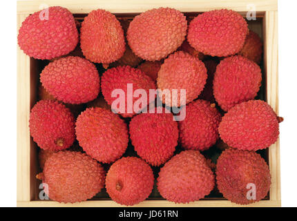 Heap of fresh picked red ripe litchee (Litchi chinensis) tropical fruits in wooden container box isolated on white background, close up, elevated top  Stock Photo