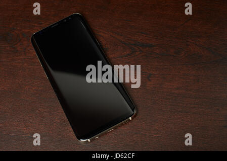 New york, USA - June 13, 2017: Samsung s8 plus smartphone lay on dark brown wooden table view from top Stock Photo