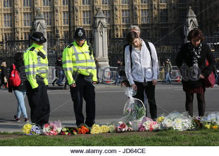 Police officers and members of the public view flowers set out in memory of PC Keith Palmer and the other victims of the London terror attack. Stock Photo