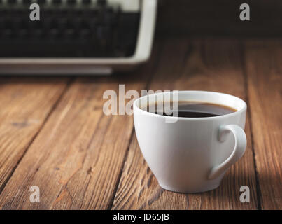 cup of coffee and old typewriter on old wooden background. Concept. Dark. Stock Photo
