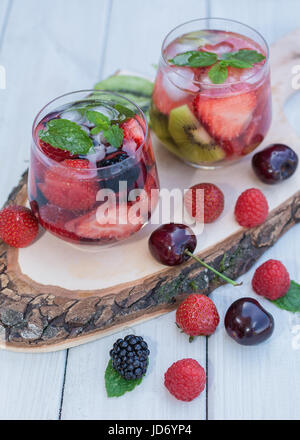 Glasses fruit water with various ingredients presented on a tree disk Stock Photo