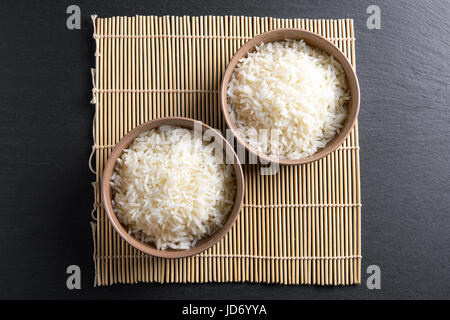 Top view: steamed cooked basmati rice in round ceramic bowls over black stone Stock Photo