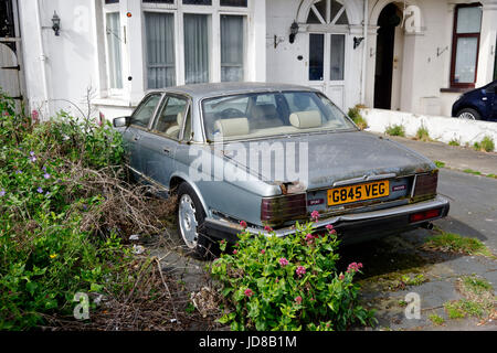 An old Jaguar XJ6, abandoned and rusting in a driveway in Clacton, Essex Stock Photo