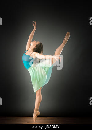 Female ballet dancer on one leg with arms outstretched, studio shot. caucasian fit pretty skinny athletic Stock Photo