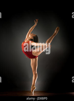 Female ballet dancer standing on one leg with arms stretched out, studio shot. caucasian fit pretty skinny athletic Stock Photo