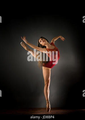 Female ballet dancer standing on one leg with arms stretched out, studio shot. caucasian fit pretty skinny athletic Stock Photo