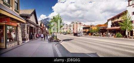 Panoramic street scenery of Banff Avenue, main street in the Town of Banff in Alberta Rockies with its gift shops and restaurants and Rocky Mountains  Stock Photo