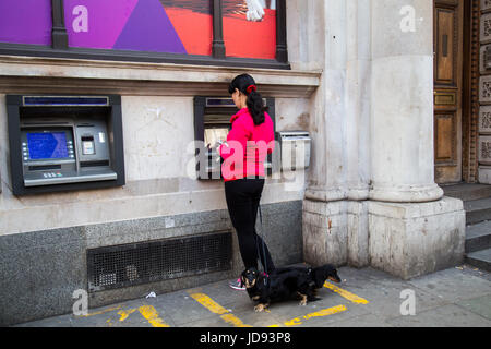UK, London - April 08, 2015: A woman is standing by an ATM with dogs Stock Photo