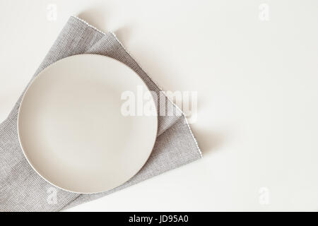 Empty plate with a napkin on white table. Top view mock up with copy space Stock Photo